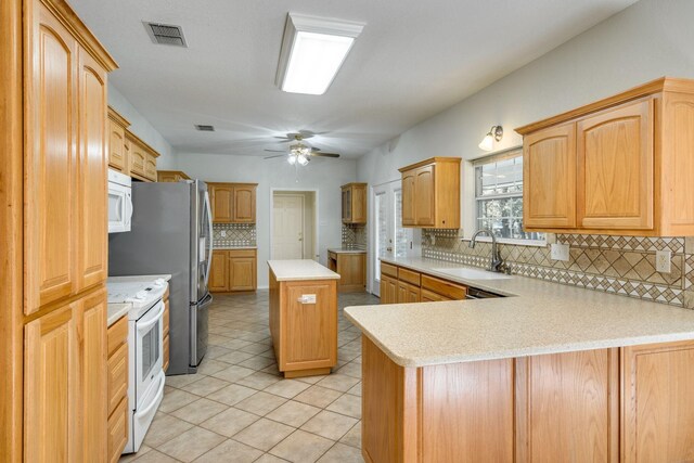 6424 County Road 176, Stephenville, TX 76401 - kitchen with a peninsula, a sink, decorative backsplash, white appliances, and ceiling fan