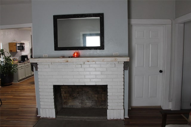 details with stainless steel microwave, a brick fireplace, and wood finished floors