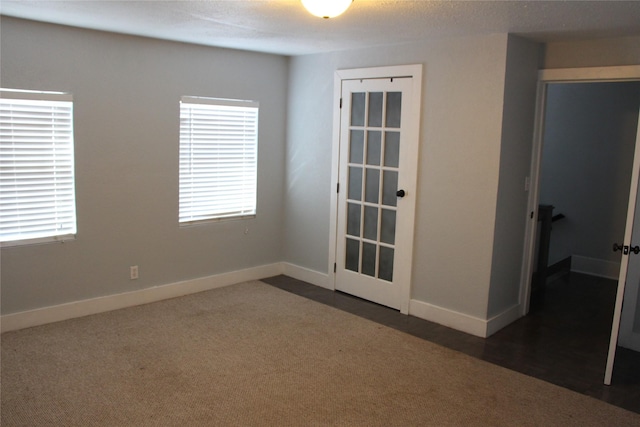 unfurnished room featuring dark colored carpet, a healthy amount of sunlight, and baseboards