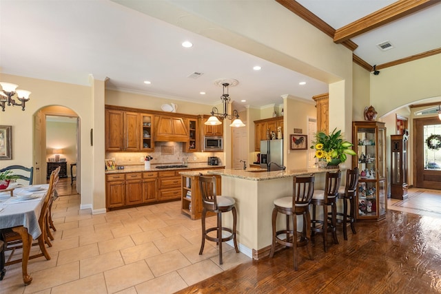 kitchen with arched walkways, brown cabinets, and stainless steel appliances