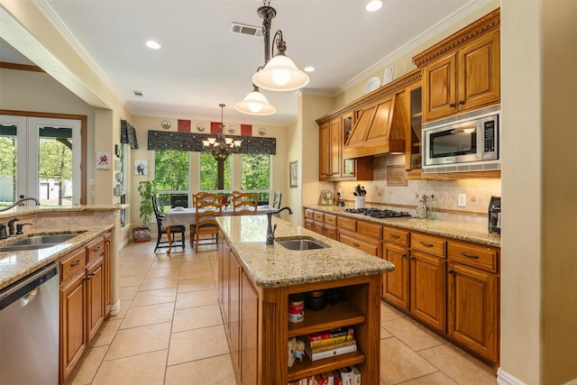 kitchen featuring brown cabinets, light stone counters, stainless steel appliances, a sink, and premium range hood