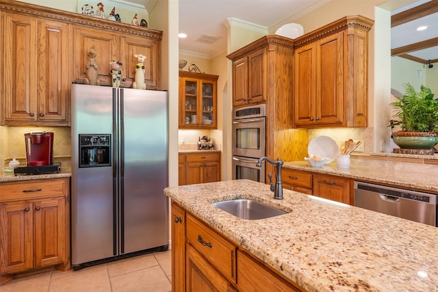 kitchen featuring ornamental molding, a sink, light stone countertops, brown cabinetry, and appliances with stainless steel finishes
