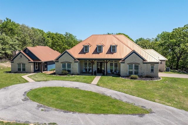 view of front of property featuring stone siding, a front lawn, and metal roof