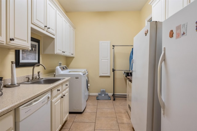 washroom featuring washer and clothes dryer, a sink, light tile patterned flooring, baseboards, and laundry area
