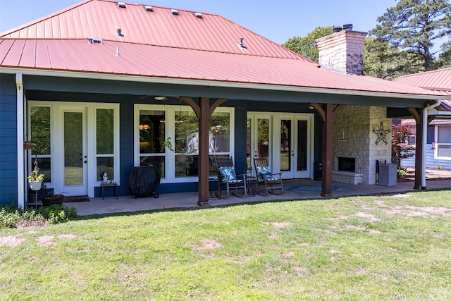 back of property with a lawn, a chimney, french doors, and metal roof