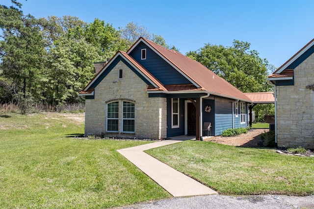 craftsman-style home featuring stone siding, a front yard, and metal roof