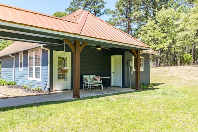 exterior space featuring a patio area, a ceiling fan, a lawn, and metal roof