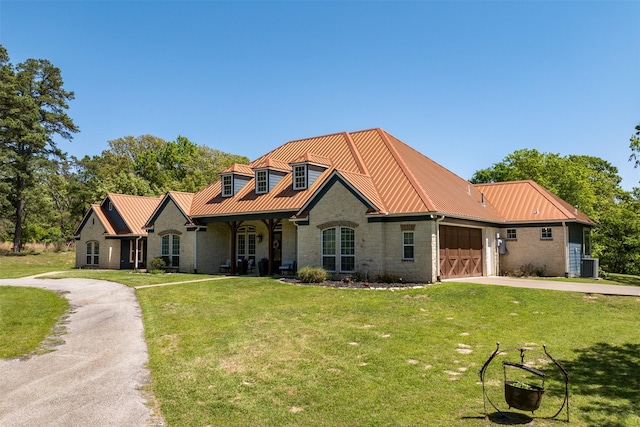 view of front of property with stone siding, concrete driveway, metal roof, a garage, and a front yard