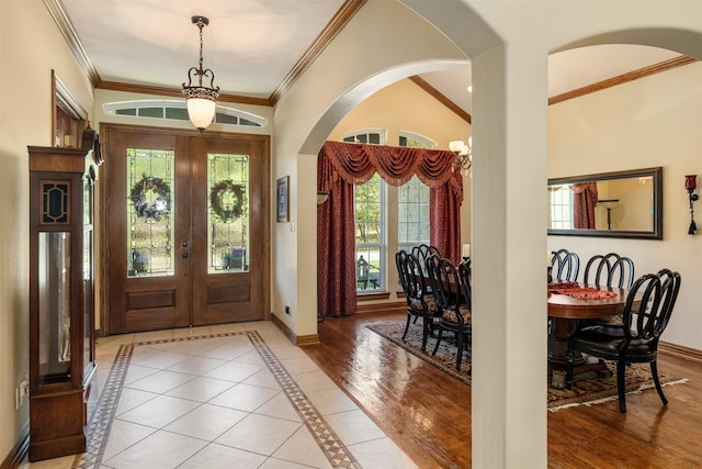 entrance foyer with french doors, baseboards, arched walkways, and crown molding