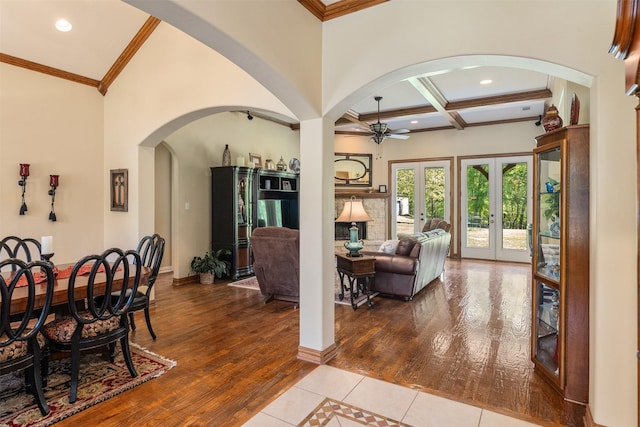 interior space featuring beam ceiling, arched walkways, coffered ceiling, a ceiling fan, and wood finished floors