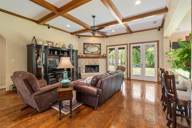 living area featuring a ceiling fan, wood finished floors, arched walkways, french doors, and coffered ceiling