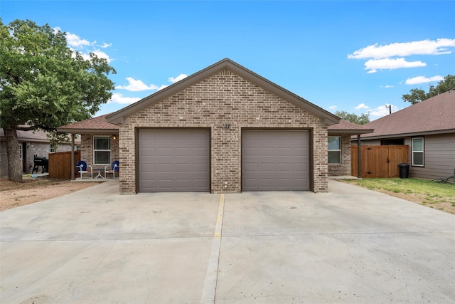 view of front of property featuring brick siding, a shingled roof, concrete driveway, and fence
