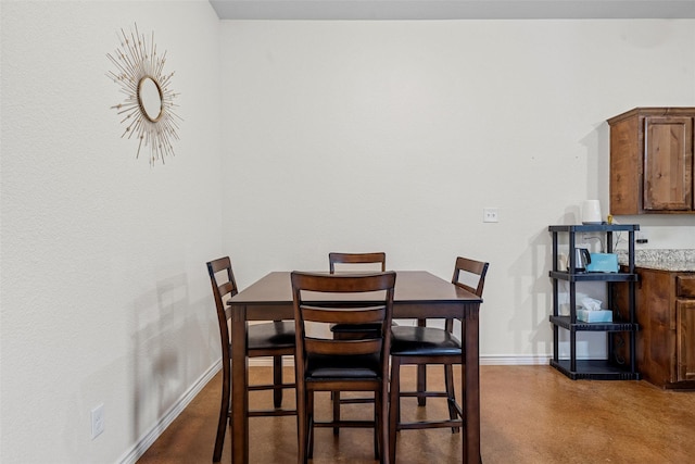 dining space with baseboards and finished concrete floors