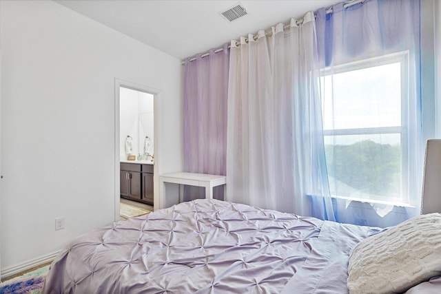 bedroom with visible vents, baseboards, and connected bathroom
