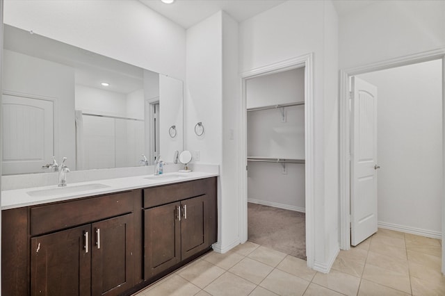 bathroom with a spacious closet, tile patterned floors, a sink, and double vanity