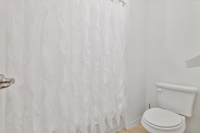bathroom featuring toilet and curtained shower