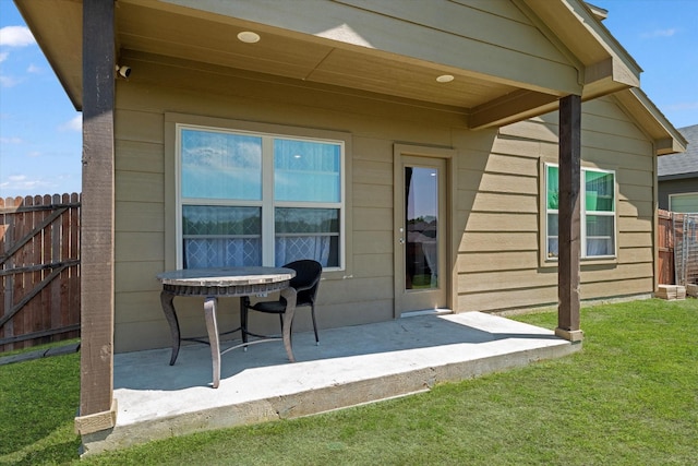 back of property featuring fence, a patio area, and a lawn