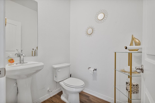 half bath featuring baseboards, wood finished floors, and toilet