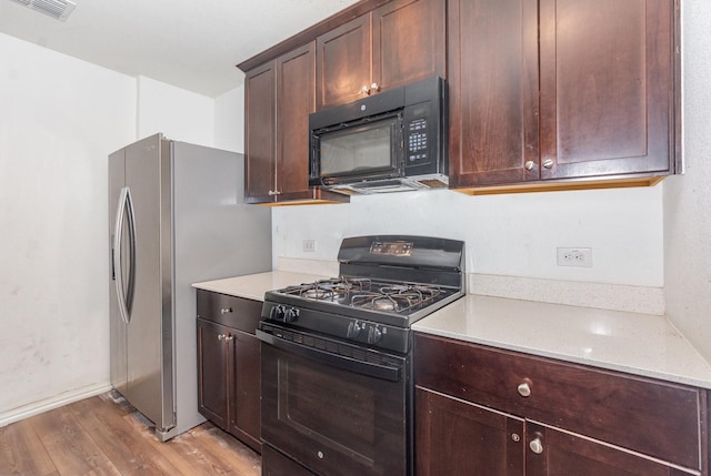 413 Everglades St, Princeton, TX 75407 - kitchen with dark brown cabinets, baseboards, light wood-type flooring, visible vents, and black appliances