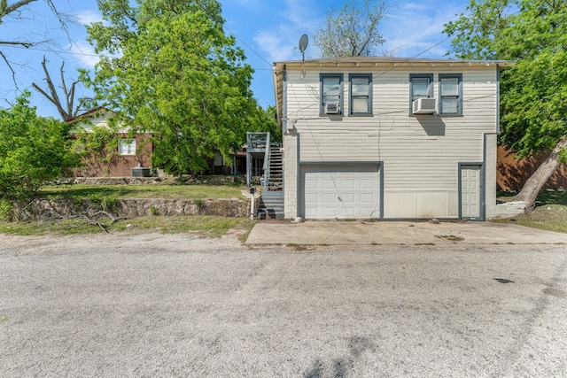 view of home's exterior featuring concrete driveway, an attached garage, stairway, and cooling unit