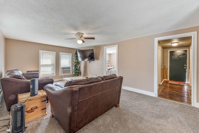 carpeted living area with ceiling fan, baseboards, a textured ceiling, and cooling unit