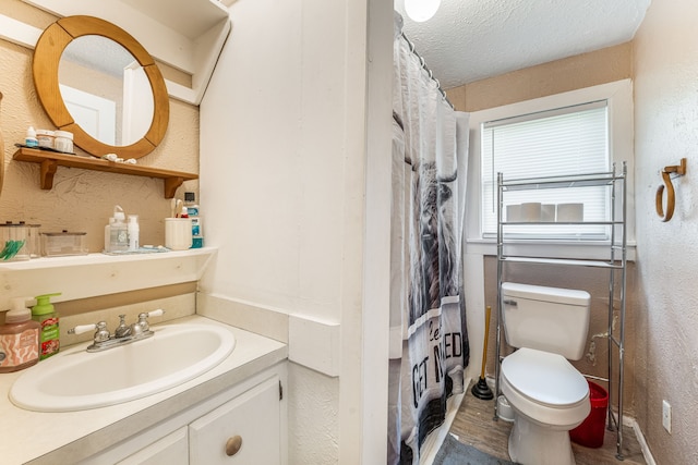 bathroom with toilet, a textured ceiling, and a textured wall