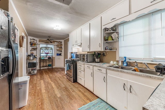 kitchen featuring stainless steel range with gas cooktop, a sink, black refrigerator with ice dispenser, open shelves, and under cabinet range hood