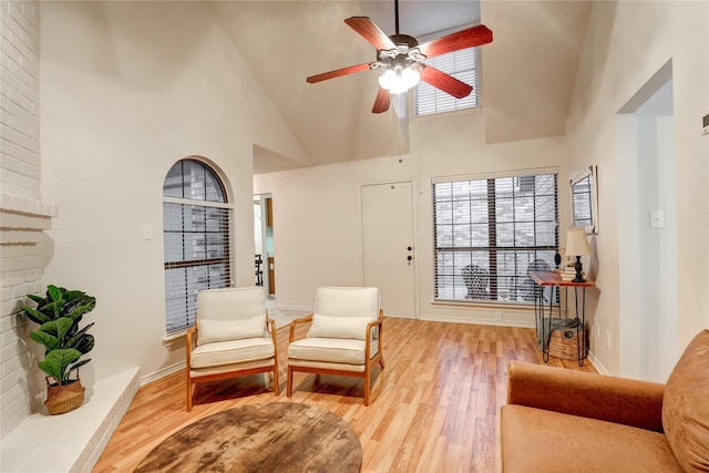 sitting room featuring baseboards, ceiling fan, light wood-style flooring, and high vaulted ceiling