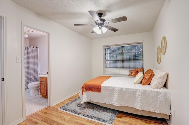 bedroom featuring a textured ceiling, ensuite bathroom, light wood-style flooring, and visible vents