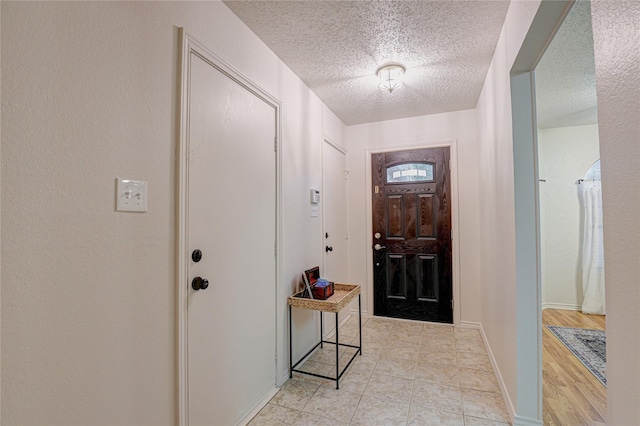 foyer entrance with baseboards and a textured ceiling