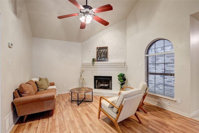 living area with a brick fireplace, lofted ceiling, baseboards, ceiling fan, and light wood-style flooring