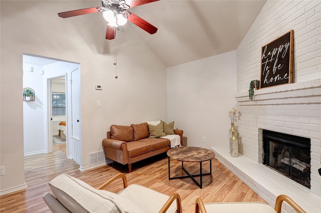 living area with visible vents, a fireplace, a ceiling fan, wood finished floors, and vaulted ceiling