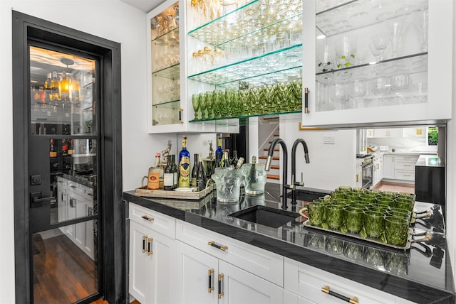 bar featuring a sink, bar, wood finished floors, refrigerator with glass door, and beverage cooler