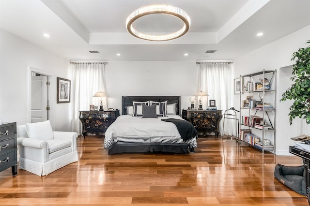 bedroom featuring wood finished floors, visible vents, and multiple windows