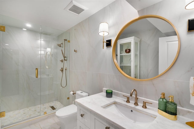 bathroom featuring visible vents, toilet, vanity, a marble finish shower, and tile walls