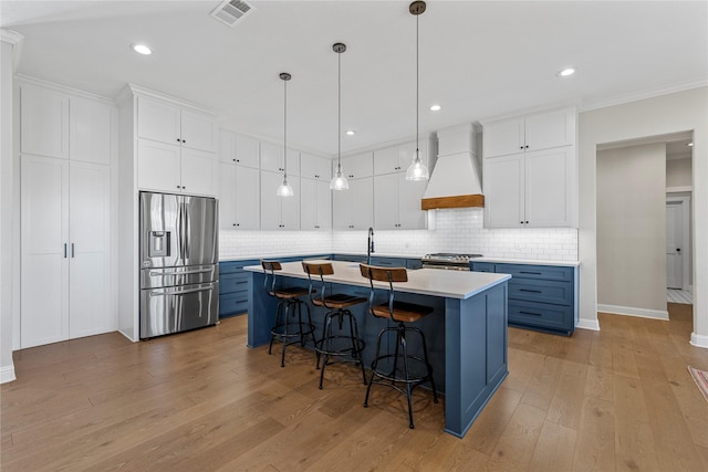 301 Wycliff Dr, Waco, TX 76633 - kitchen featuring a kitchen breakfast bar, blue cabinets, stainless steel appliances, premium range hood, and visible vents