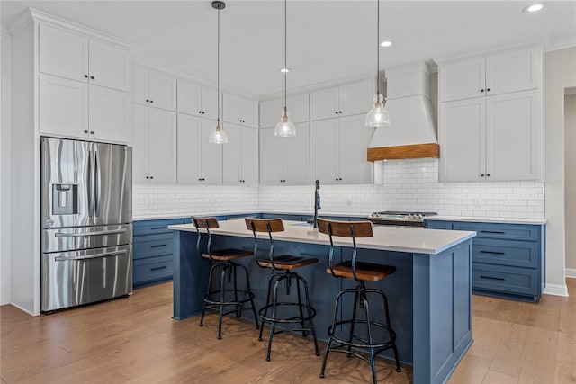 301 Wycliff Dr, Waco, TX 76633 - kitchen featuring light wood-style floors, custom range hood, blue cabinetry, light countertops, and appliances with stainless steel finishes
