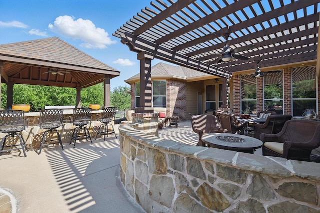 view of patio featuring a gazebo, a ceiling fan, and an outdoor fire pit