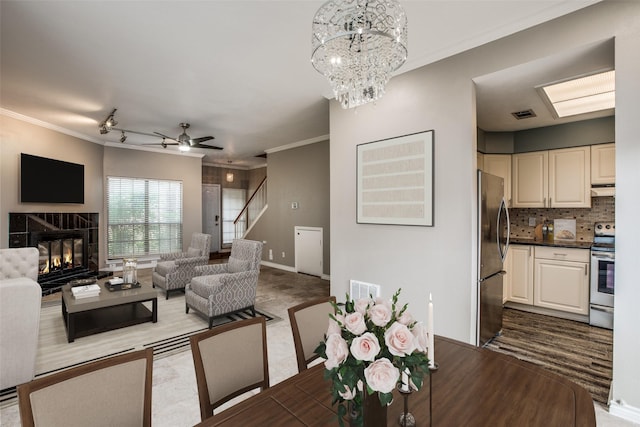 9910 Royal Ln Unit 1402, Dallas, TX 75231 - living room featuring a tile fireplace, stairway, a chandelier, ornamental molding, and a ceiling fan