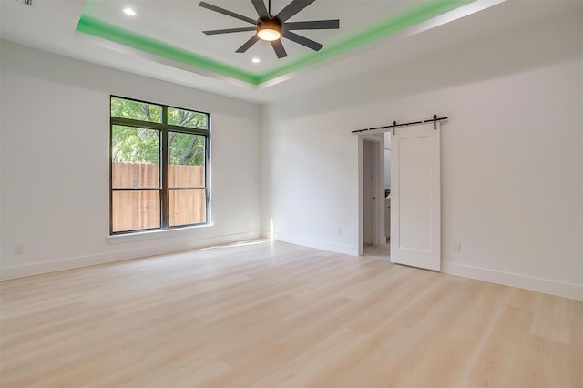 2229 Varsity Dr, Grand Prairie, TX 75051 - empty room with a barn door, recessed lighting, a tray ceiling, light wood-style floors, and ceiling fan