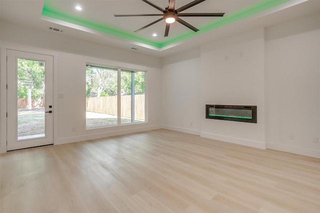 2229 Varsity Dr, Grand Prairie, TX 75051 - unfurnished living room featuring a glass covered fireplace, light wood-style floors, a raised ceiling, visible vents, and recessed lighting