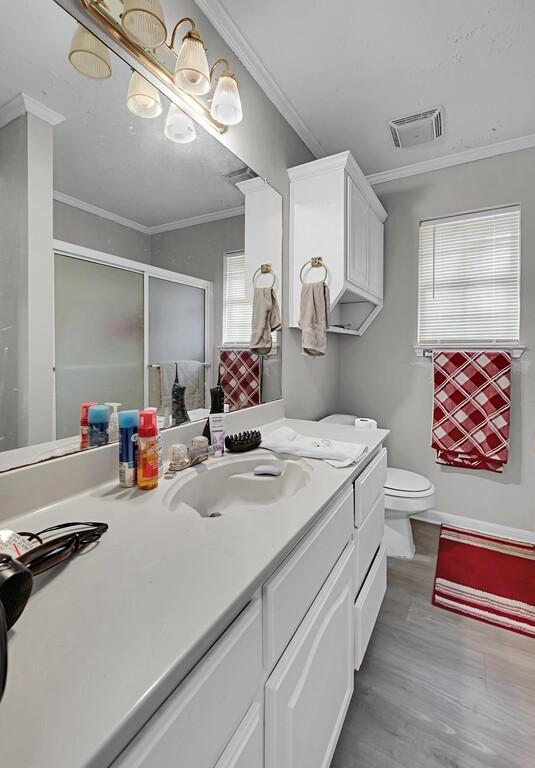 2618 S 2nd St, Waco, TX 76706 - bathroom featuring wood finished floors, visible vents, toilet, vanity, and a stall shower