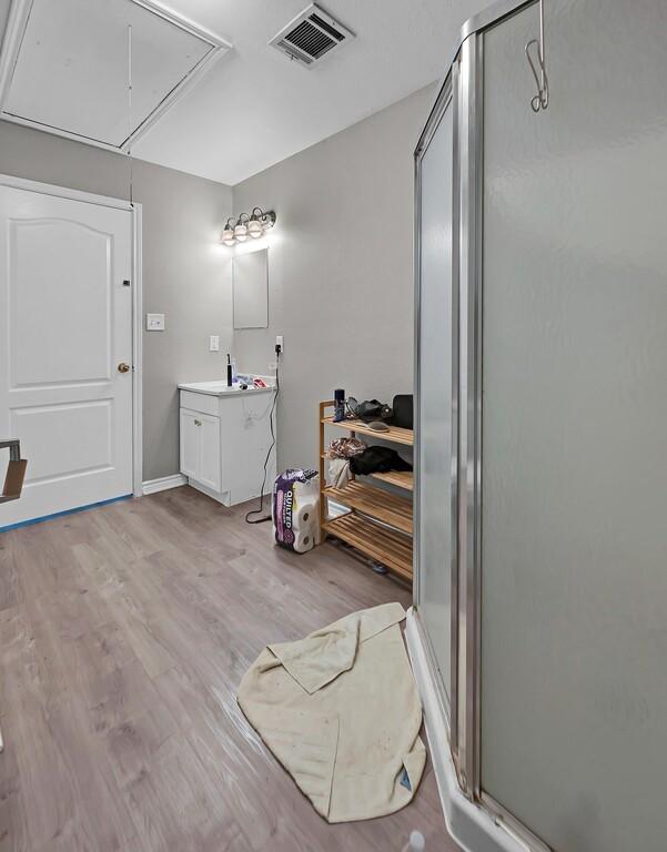 2618 S 2nd St, Waco, TX 76706 - full bathroom with vanity, wood finished floors, visible vents, and a stall shower