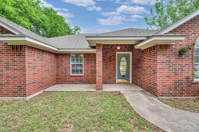 2618 S 2nd St, Waco, TX 76706 - view of exterior entry featuring a lawn, brick siding, and a shingled roof