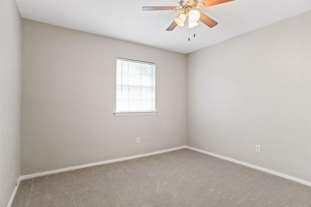 carpeted spare room with a ceiling fan and baseboards