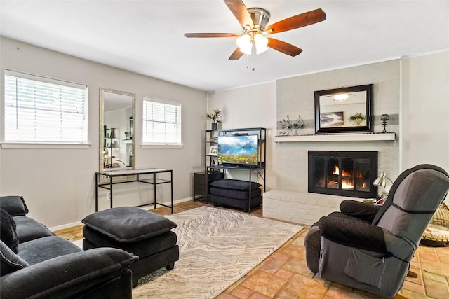 living area featuring baseboards, a brick fireplace, and ceiling fan