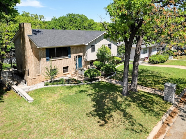 split foyer home with fence, a chimney, brick siding, and a front yard