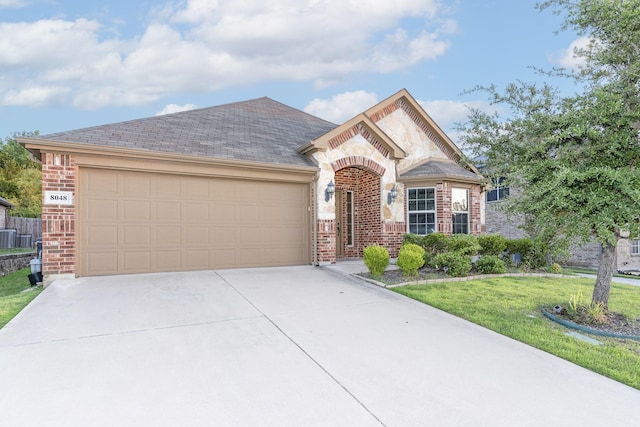 french country style house featuring driveway, central AC, brick siding, an attached garage, and a front yard