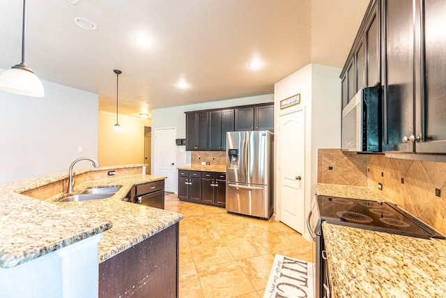 kitchen with tasteful backsplash, a sink, hanging light fixtures, appliances with stainless steel finishes, and light stone countertops