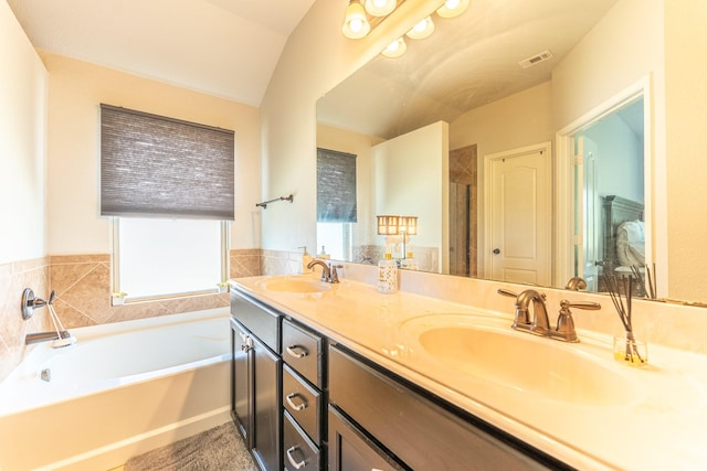 full bath featuring a bath, a sink, visible vents, and double vanity